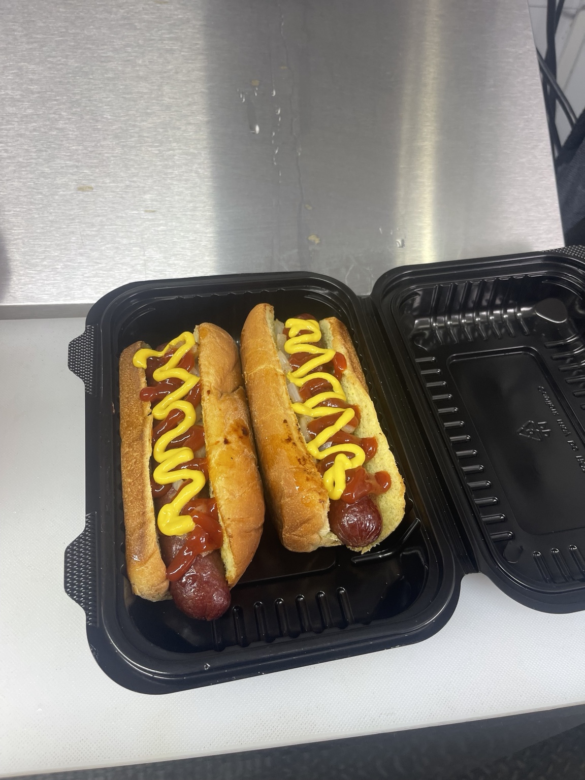 Two hot dogs in buns with ketchup and mustard